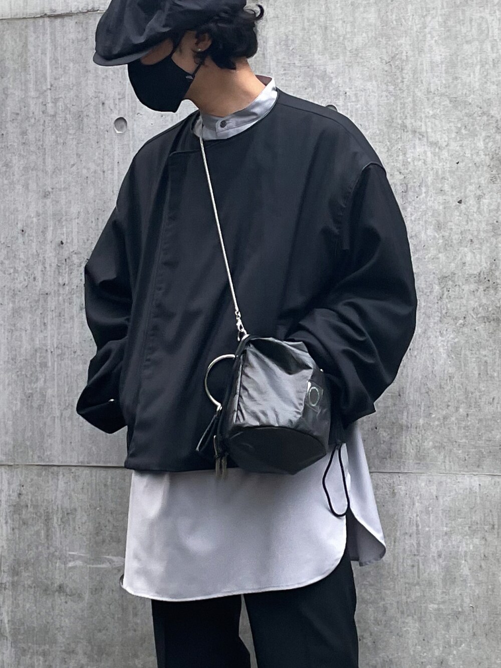 ブラック系のノーカラージャケット、ブラック系のショルダーバッグ、ブラック系のスラックスを着用したメンズの春コーディネートの2枚目の写真