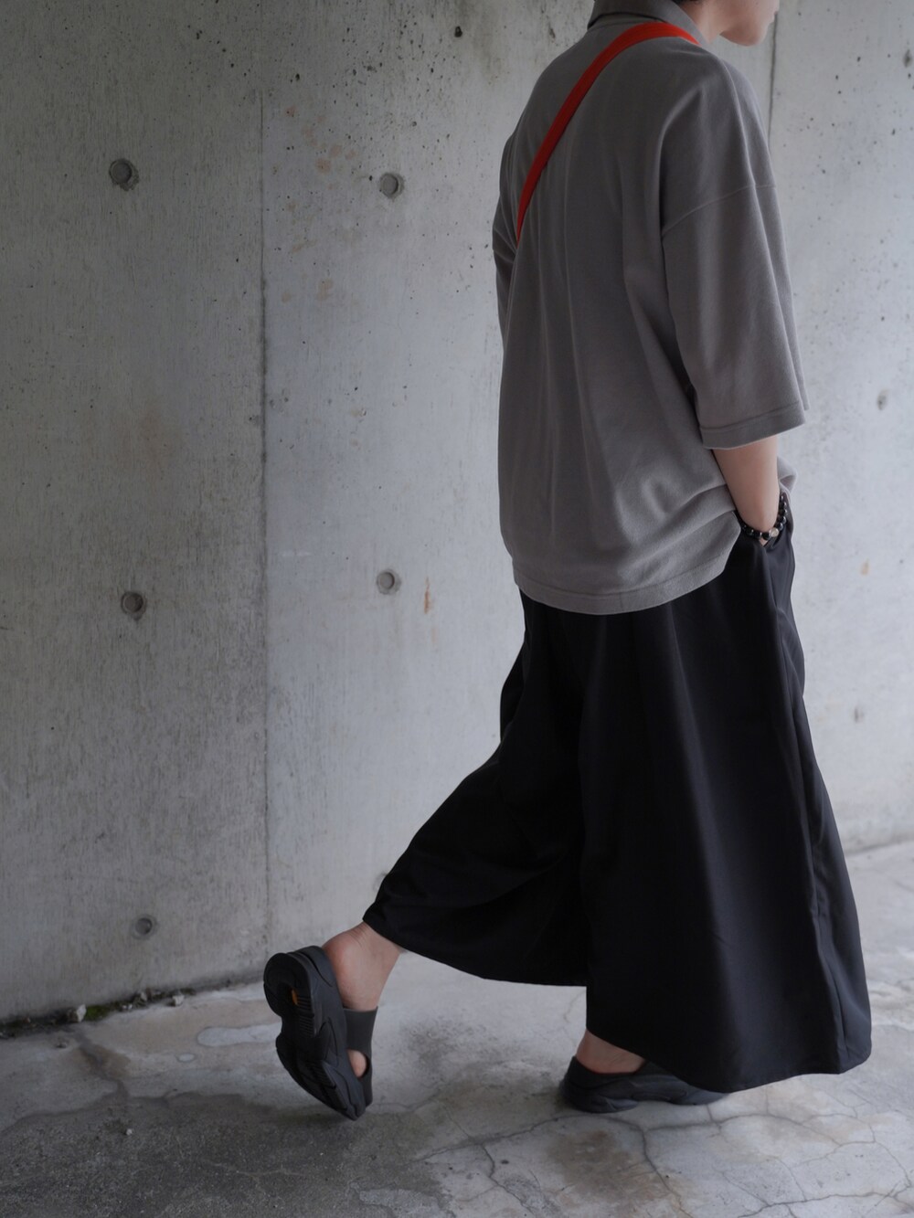 ブラック系のスラックス、ブラック系のサンダル、ベージュ系のポロシャツを着用したメンズの夏コーディネートの3枚目の写真