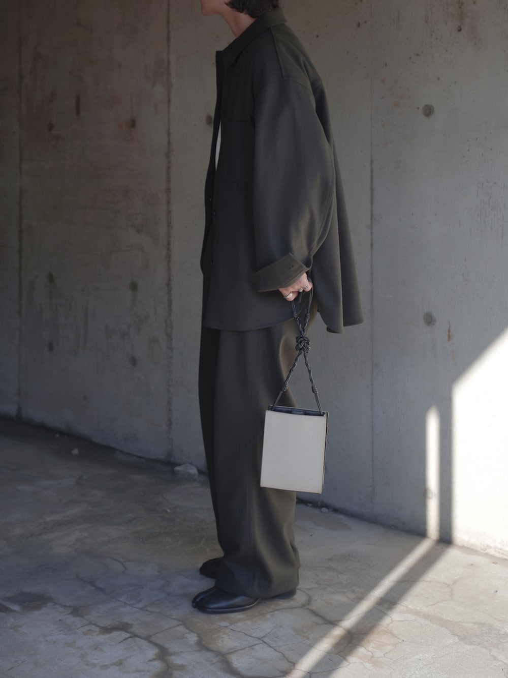 グリーン系のパンツ、ブラック系のブーツ、ホワイト系のショルダーバッグを着用したメンズの秋コーディネートの2枚目の写真