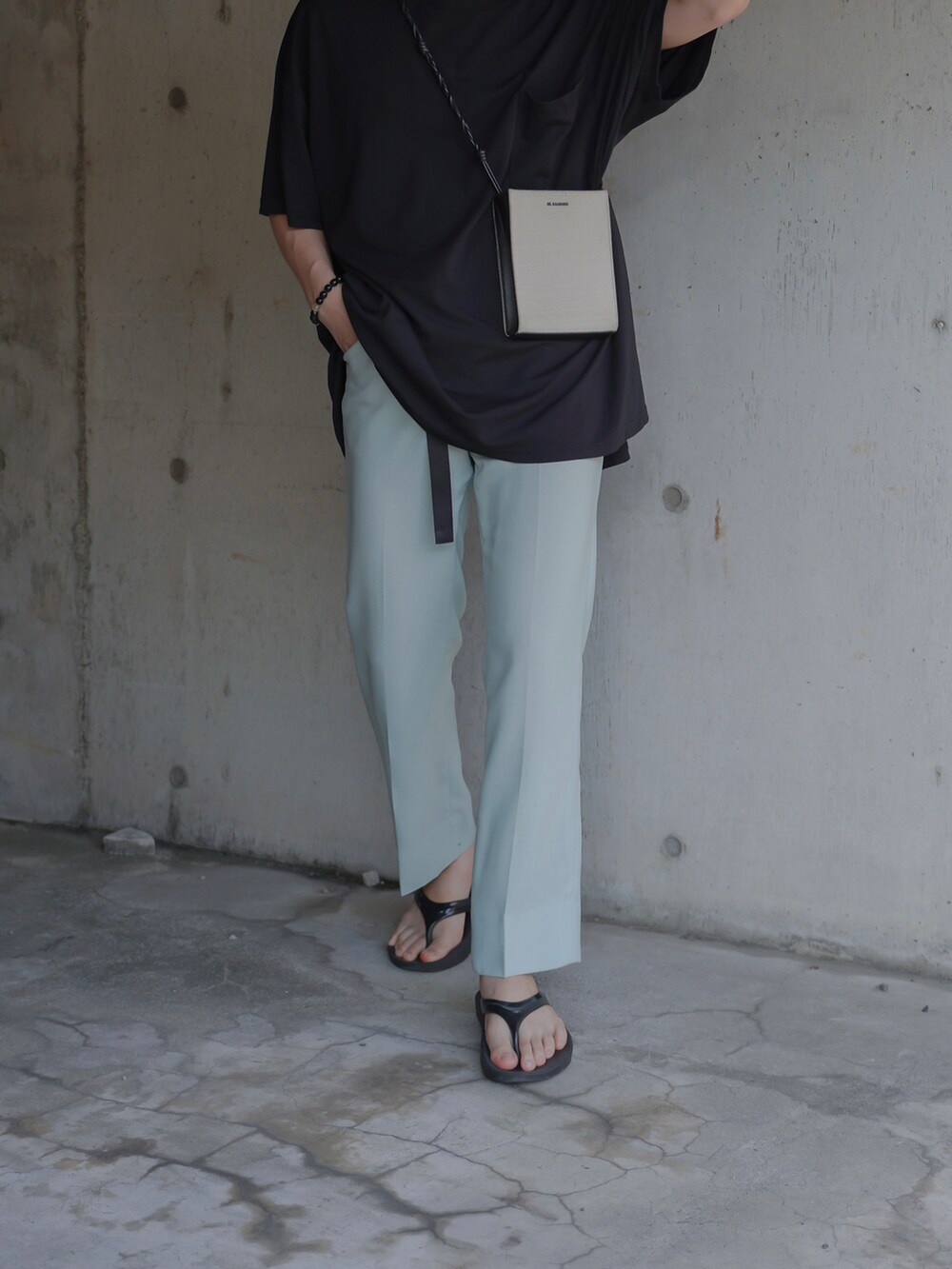 グリーン系のスラックス、ブラック系のサンダル、ホワイト系のショルダーバッグを着用したメンズの夏コーディネートの4枚目の写真