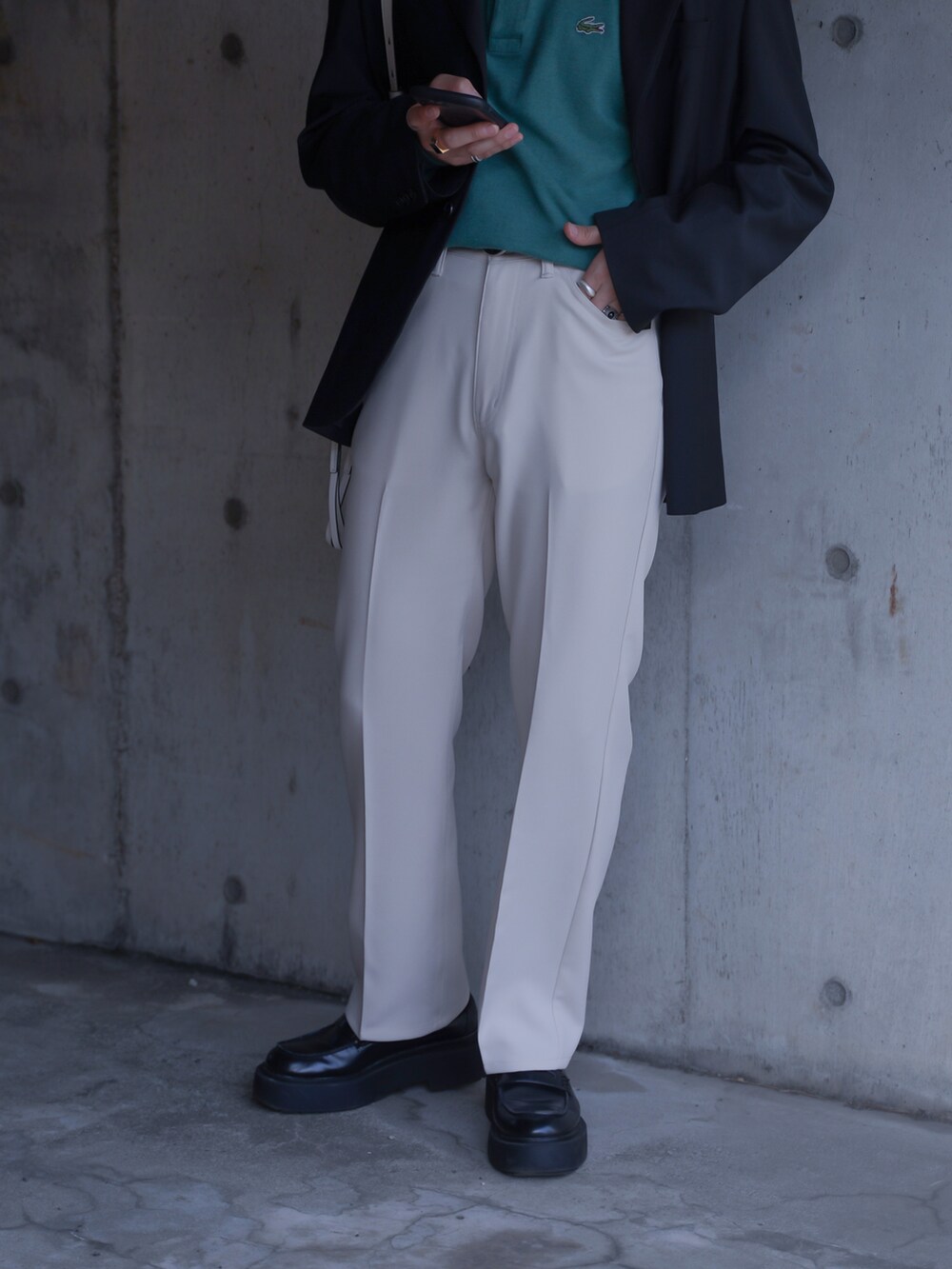 グリーン系のポロシャツ、ブラック系のテーラードジャケット、ホワイト系のショルダーバッグを着用したメンズの春コーディネートの4枚目の写真