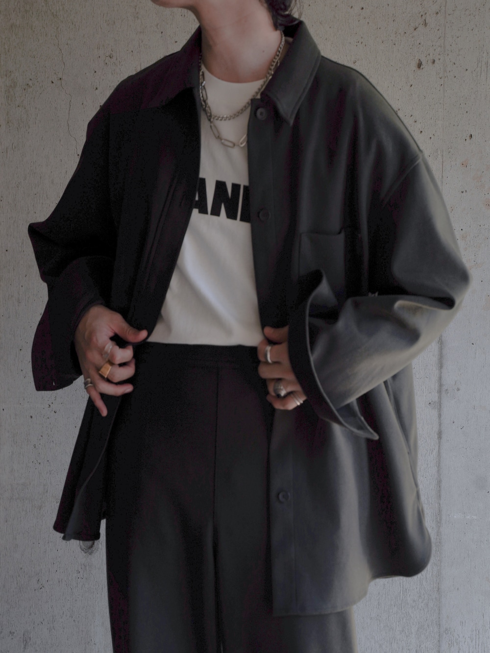 グリーン系のパンツ、ブラック系のブーツ、ホワイト系のショルダーバッグを着用したメンズの秋コーディネートの3枚目の写真