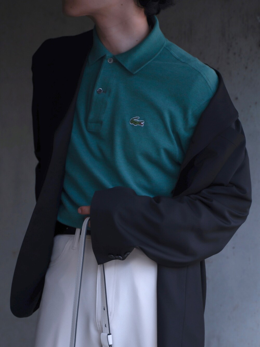 グリーン系のポロシャツ、ブラック系のテーラードジャケット、ホワイト系のショルダーバッグを着用したメンズの春コーディネートの3枚目の写真