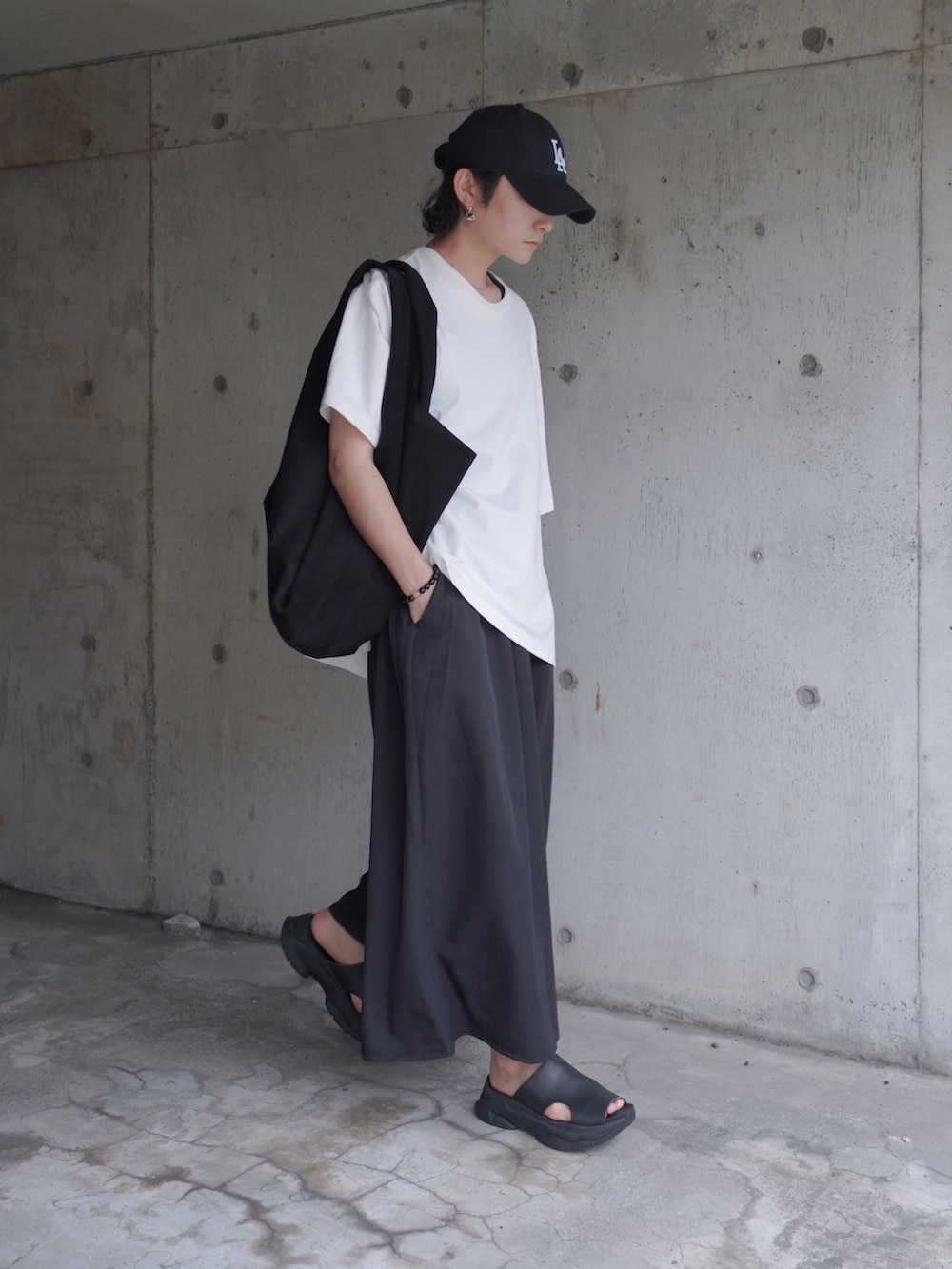 ブラック系のサンダル、ブラック系のスラックス、ホワイト系のTシャツ/カットソーを着用したメンズの夏コーディネートの2枚目の写真