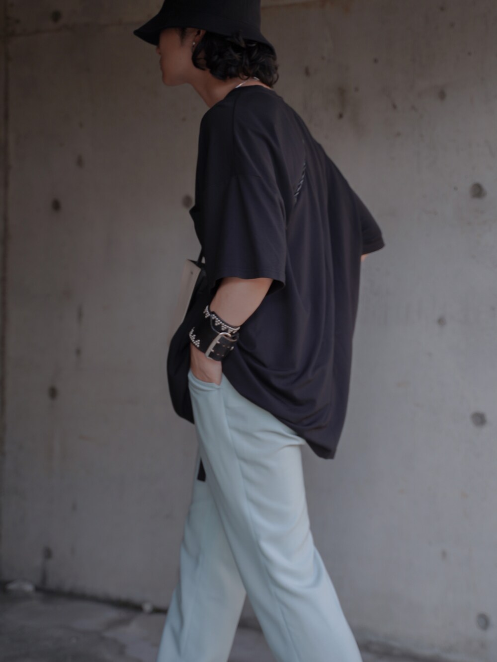 グリーン系のスラックス、ブラック系のサンダル、ホワイト系のショルダーバッグを着用したメンズの夏コーディネートの3枚目の写真