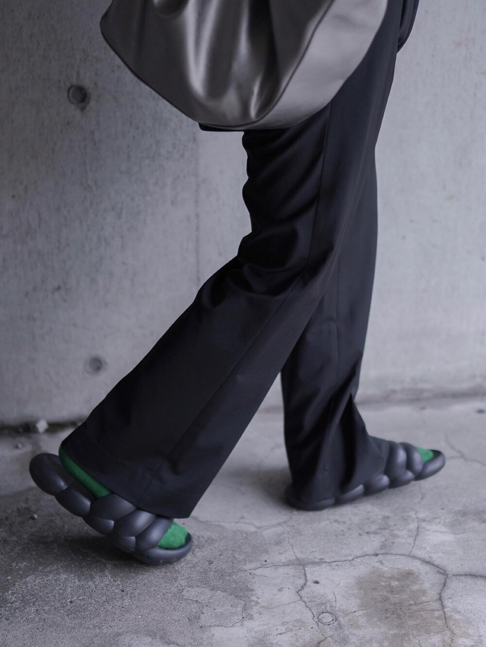 ブラック系のスラックス、ブラック系のパーカー、シルバー系のトートバッグを着用したメンズの夏コーディネートの3枚目の写真