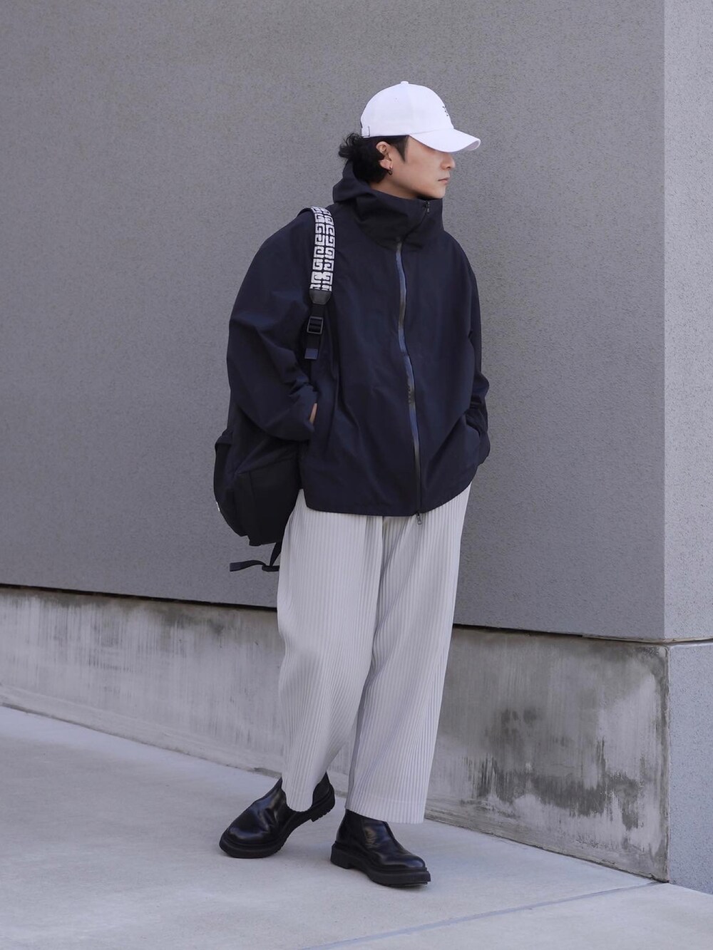 ブラック系のバックパック/リュック、ブラック系のマウンテンパーカー、グレー系のパンツを着用したメンズの春コーディネートの4枚目の写真