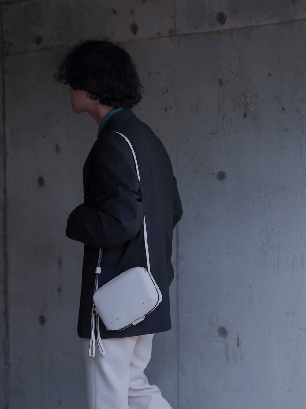 グリーン系のポロシャツ、ブラック系のテーラードジャケット、ホワイト系のショルダーバッグを着用したメンズの春コーディネートの2枚目の写真