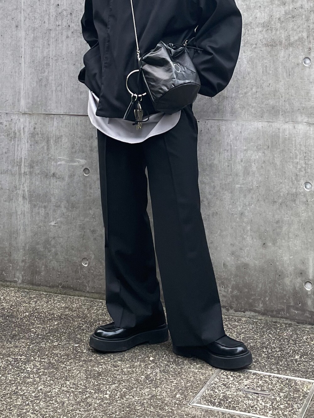 ブラック系のノーカラージャケット、ブラック系のショルダーバッグ、ブラック系のスラックスを着用したメンズの春コーディネートの3枚目の写真