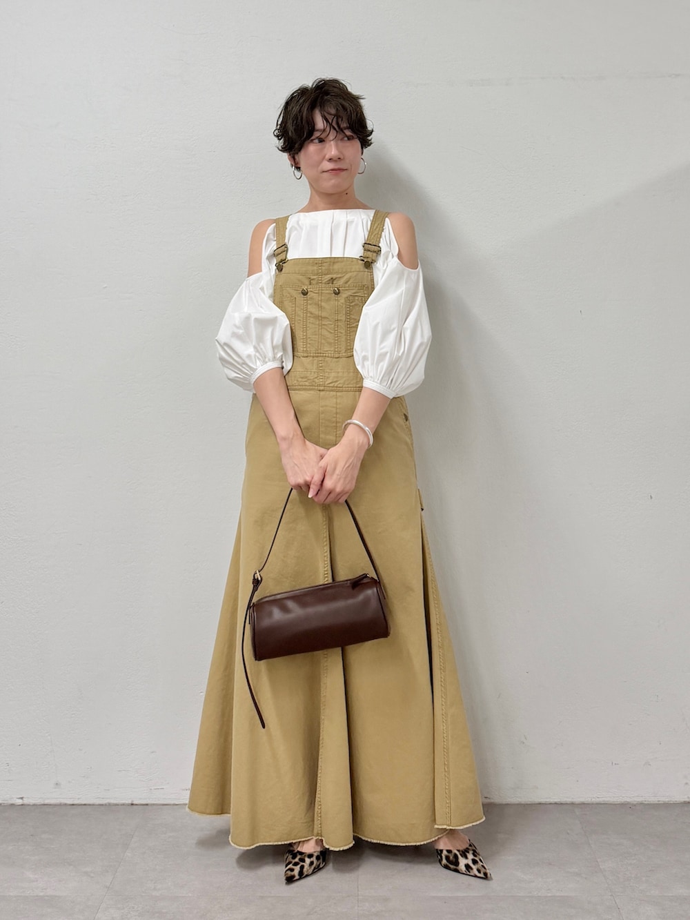 イエロー系のジャンパースカート、ブラウン系のショルダーバッグ、イエロー系のパンプスを着用したレディースの冬コーディネートの3枚目の写真