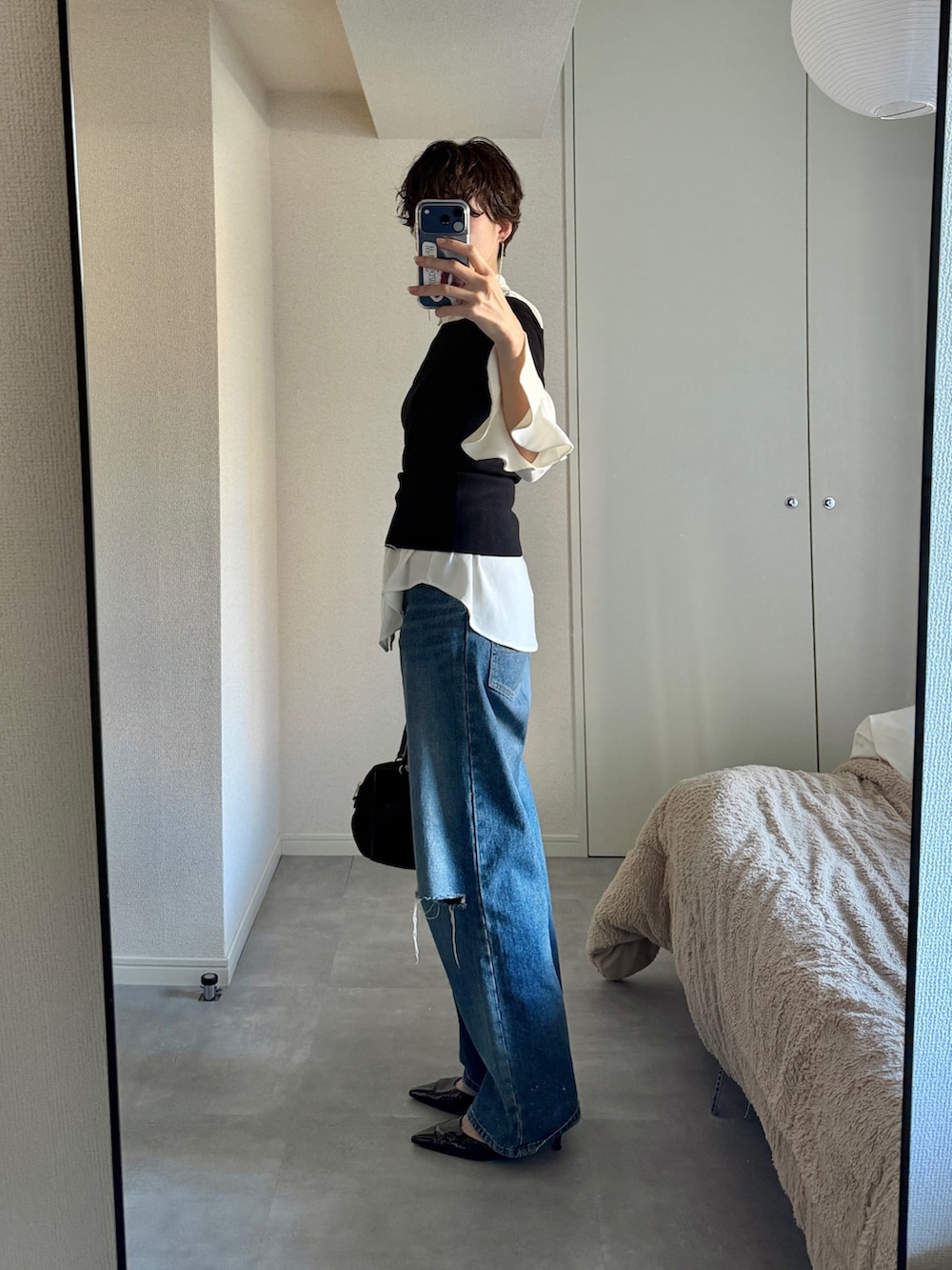 ブルー系のデニムパンツ、ブラック系のニット/セーター、ブラウン系のパンプスを着用したレディースの冬コーディネートの2枚目の写真