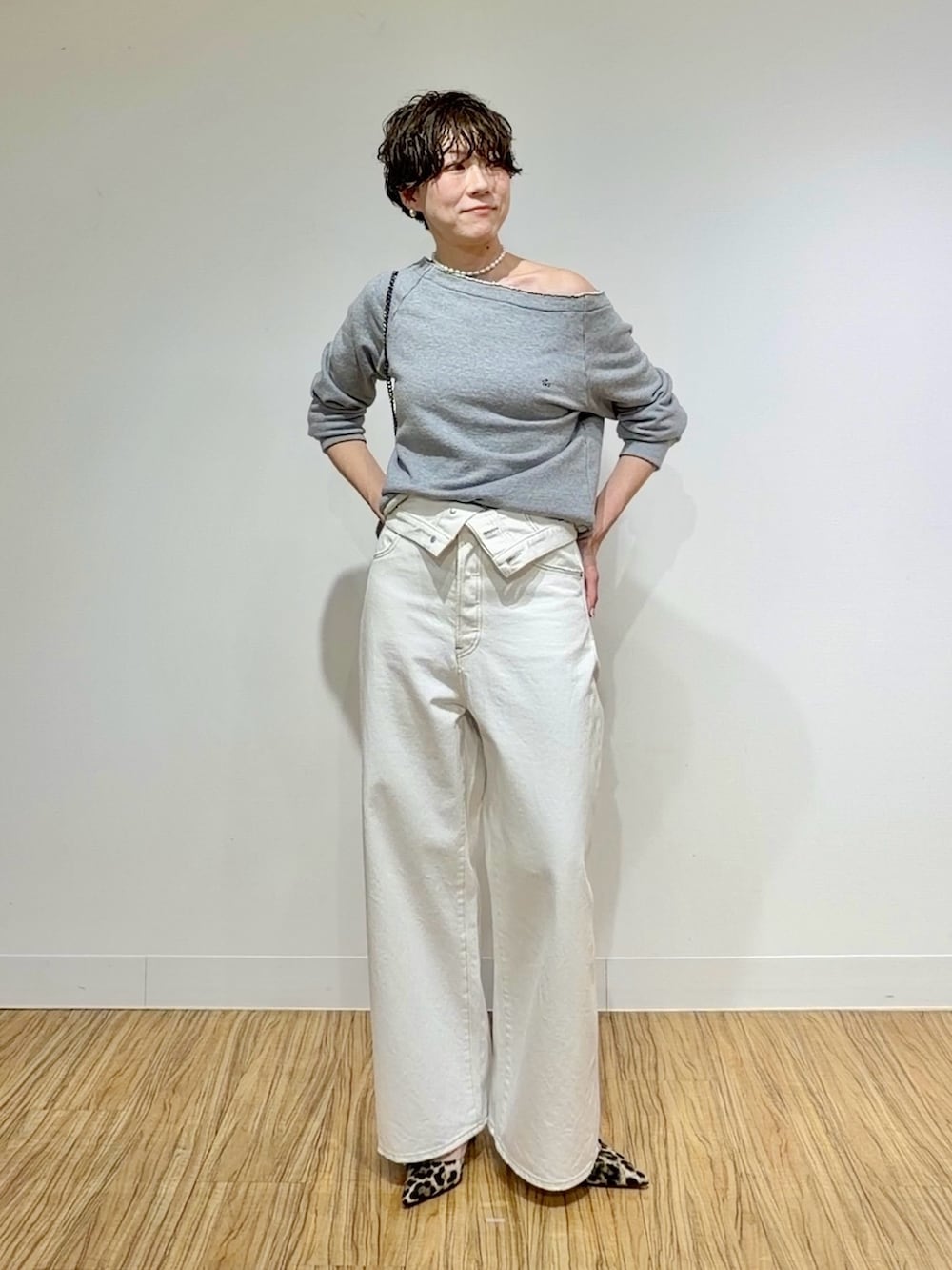 グレー系のスウェット、ホワイト系のデニムパンツ、グレー系のショルダーバッグを着用したレディースの冬コーディネートの2枚目の写真