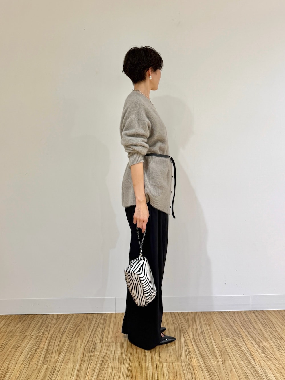 ブラウン系のカーディガン/ボレロ、ブラック系のその他パンツ、ホワイト系のクラッチバッグを着用したレディースの秋コーディネートの3枚目の写真