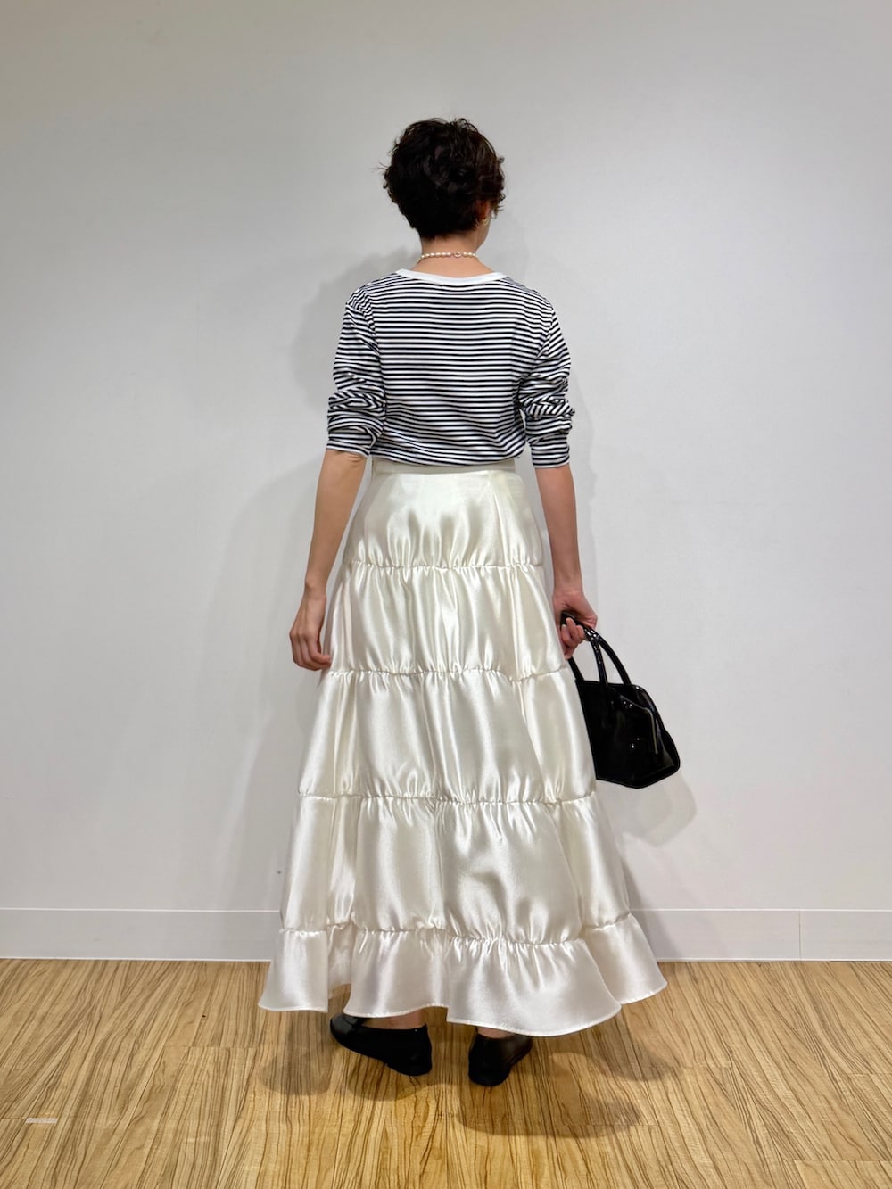 ブラック系のTシャツ/カットソー、ブラック系のボストンバッグ、ホワイト系のスカートを着用したレディースの冬コーディネートの4枚目の写真