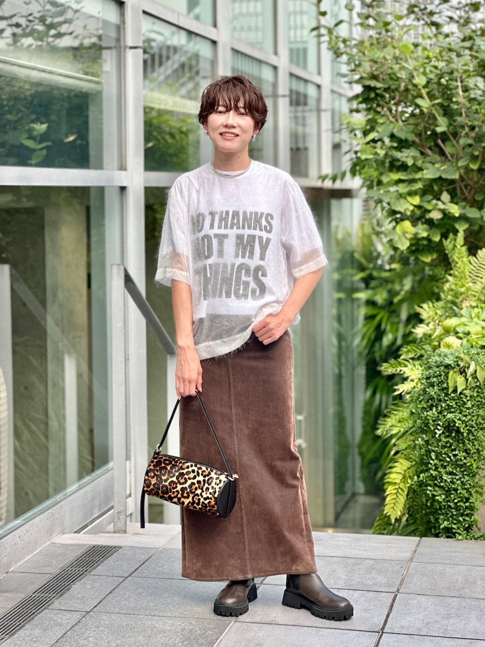 ブラック系のブーツ、ホワイト系のTシャツ/カットソー、ブラウン系のデニムスカートを着用したレディースの夏コーディネートの2枚目の写真