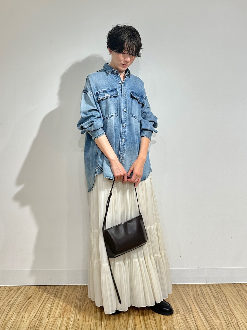 ブルー系のシャツ/ブラウス、ホワイト系のスカート、ブラウン系のショルダーバッグを着用したレディースの冬コーディネートの2枚目の写真