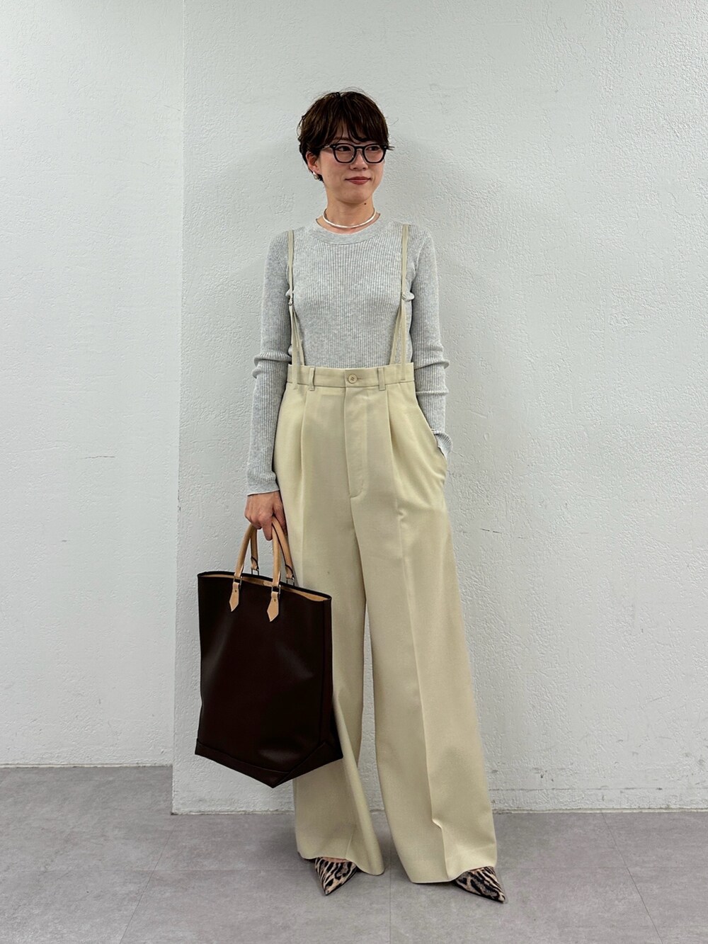 ベージュ系のスラックス、グレー系のニット/セーター、シルバー系のピアス（両耳用）を着用したレディースの冬コーディネートの2枚目の写真