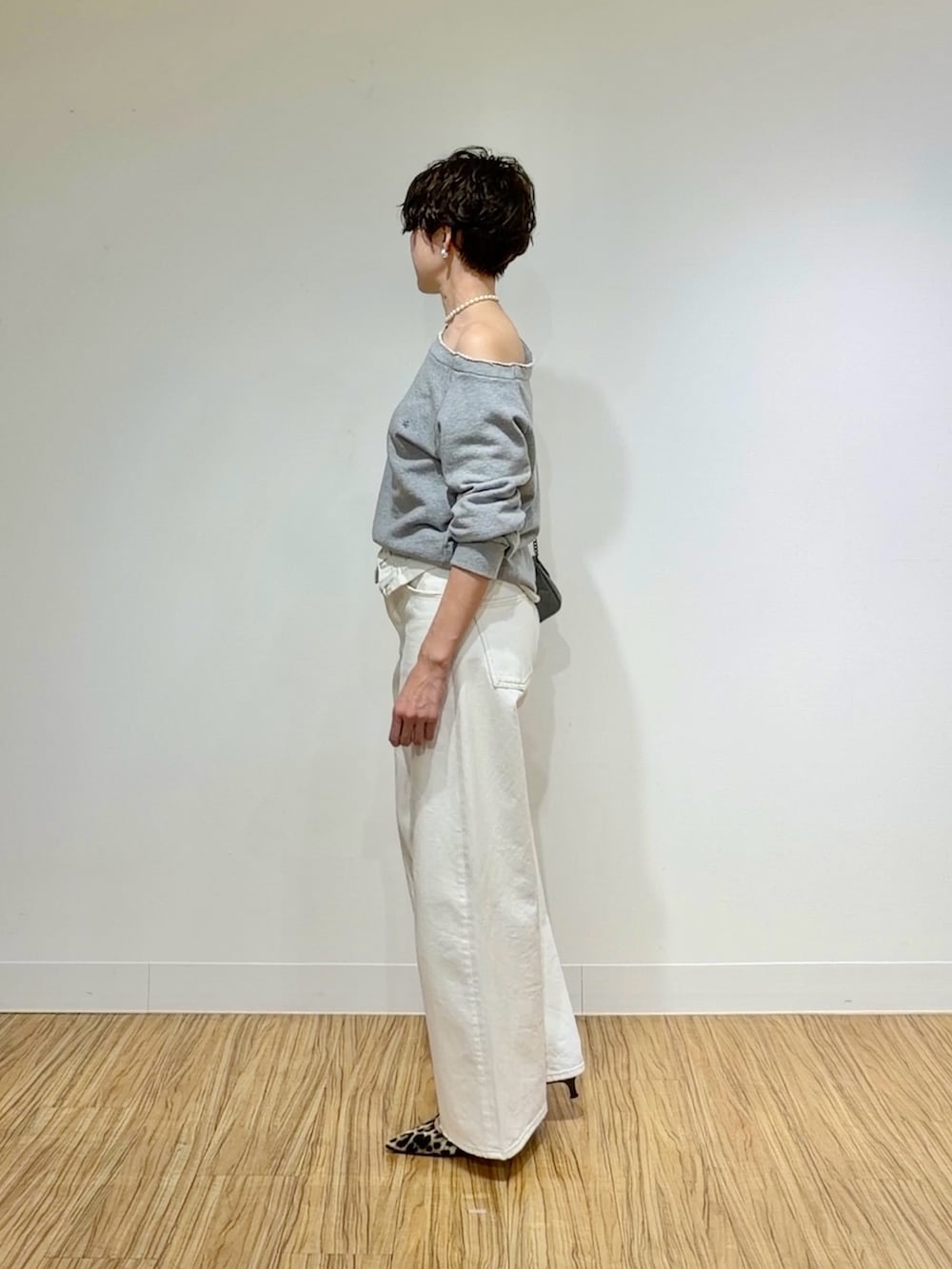 グレー系のスウェット、ホワイト系のデニムパンツ、グレー系のショルダーバッグを着用したレディースの冬コーディネートの5枚目の写真