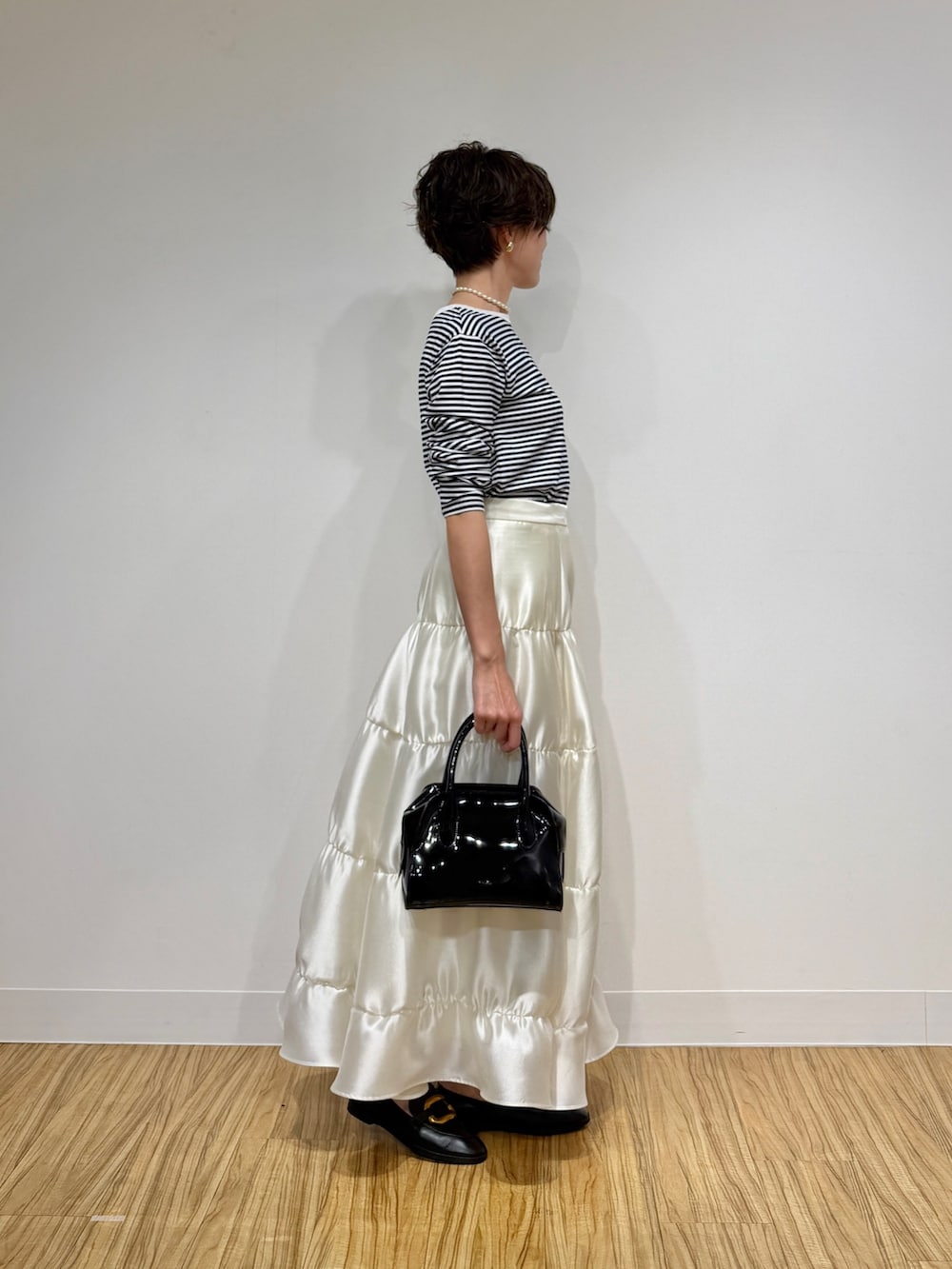 ブラック系のTシャツ/カットソー、ブラック系のボストンバッグ、ホワイト系のスカートを着用したレディースの冬コーディネートの3枚目の写真