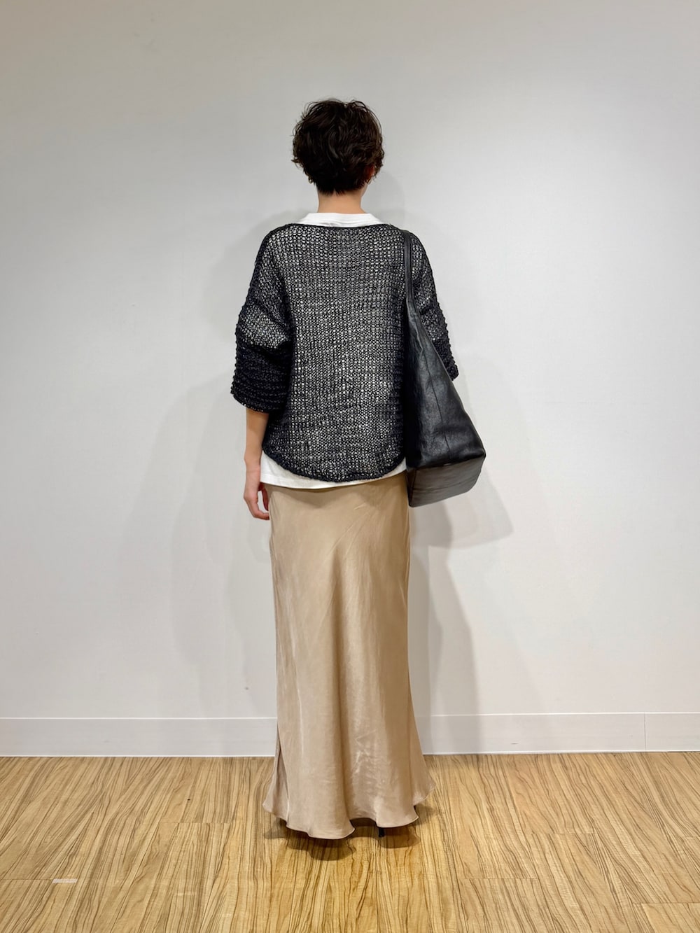 ホワイト系のTシャツ/カットソー、グレー系のニット/セーター、ベージュ系のスカートを着用したレディースの冬コーディネートの4枚目の写真