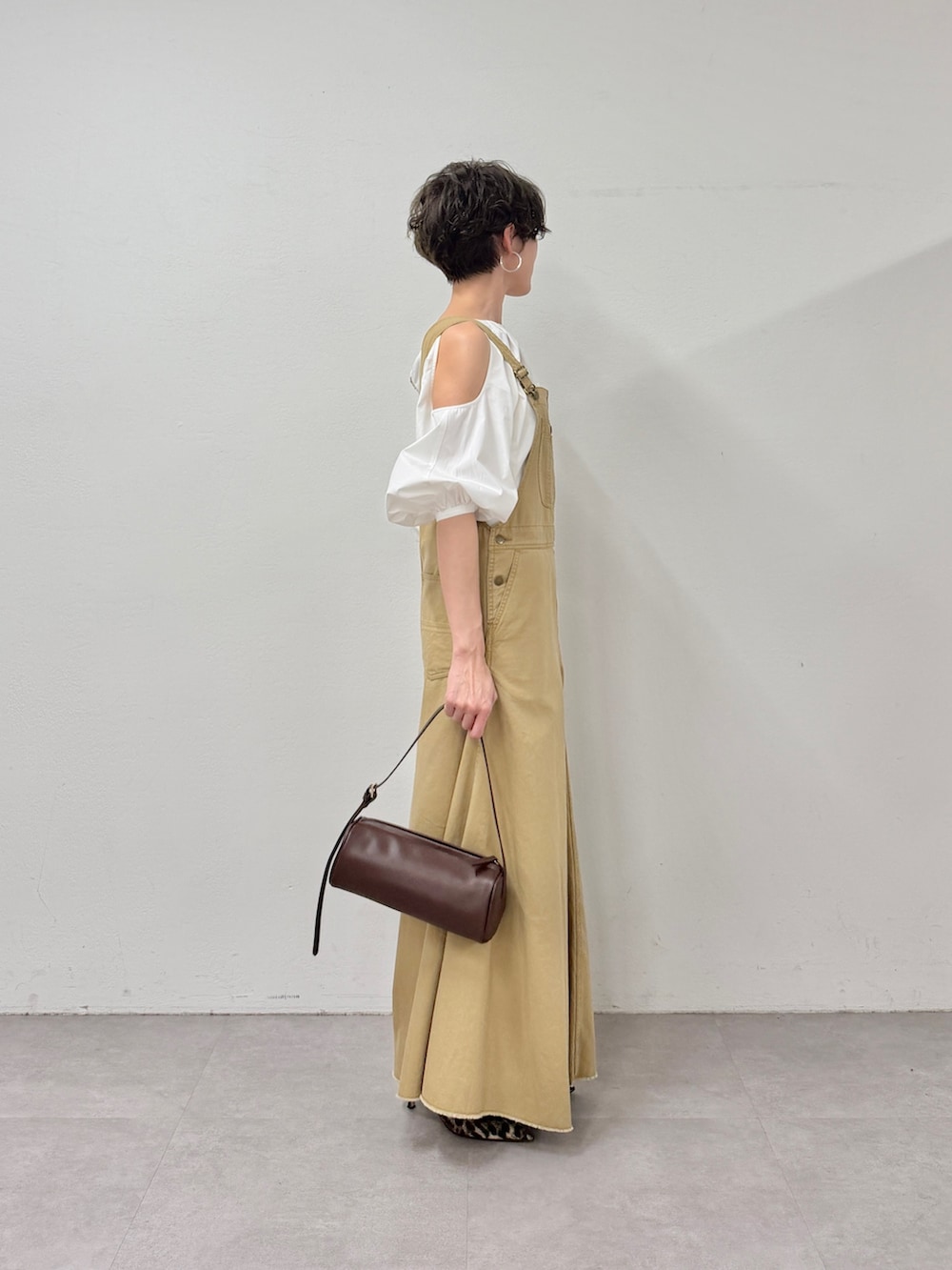 イエロー系のジャンパースカート、ブラウン系のショルダーバッグ、イエロー系のパンプスを着用したレディースの冬コーディネートの4枚目の写真