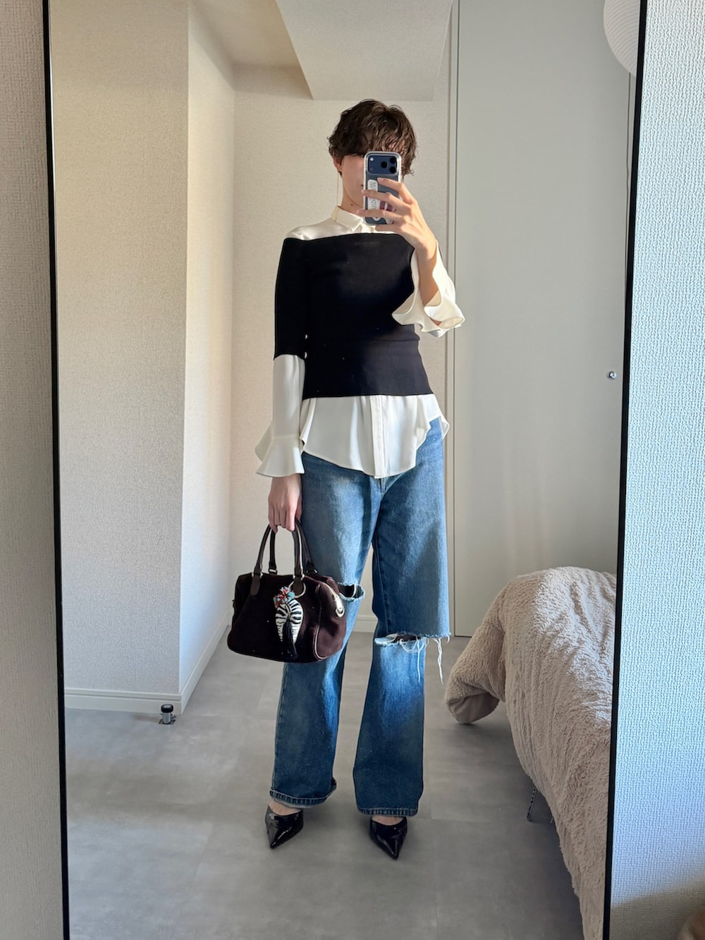 ブルー系のデニムパンツ、ブラック系のニット/セーター、ブラウン系のパンプスを着用したレディースの冬コーディネートの3枚目の写真