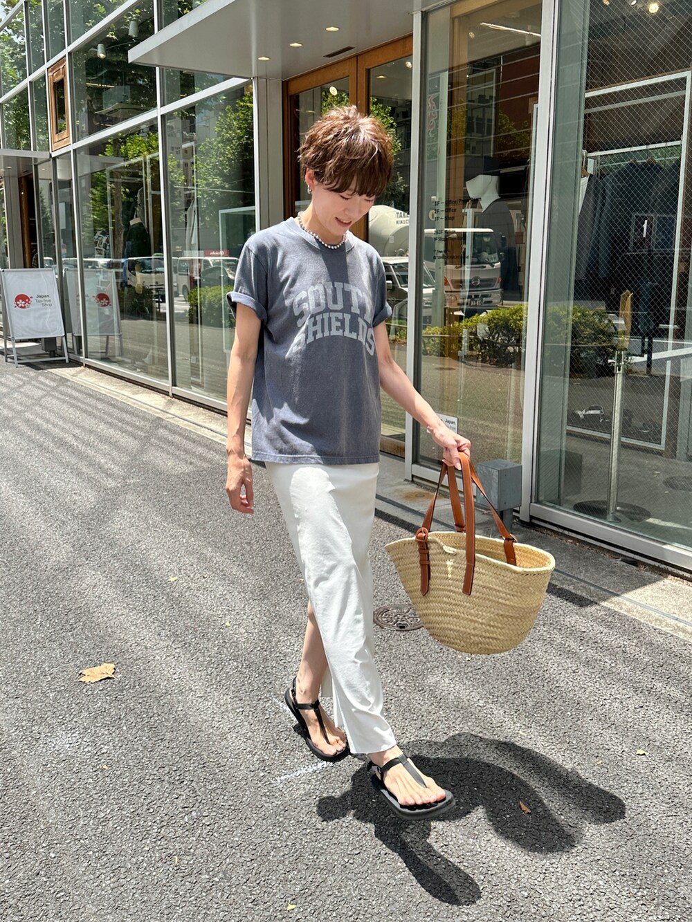 ブルー系のTシャツ/カットソー、ベージュ系のバッグ、ホワイト系のスカートを着用したレディースの夏コーディネートの2枚目の写真