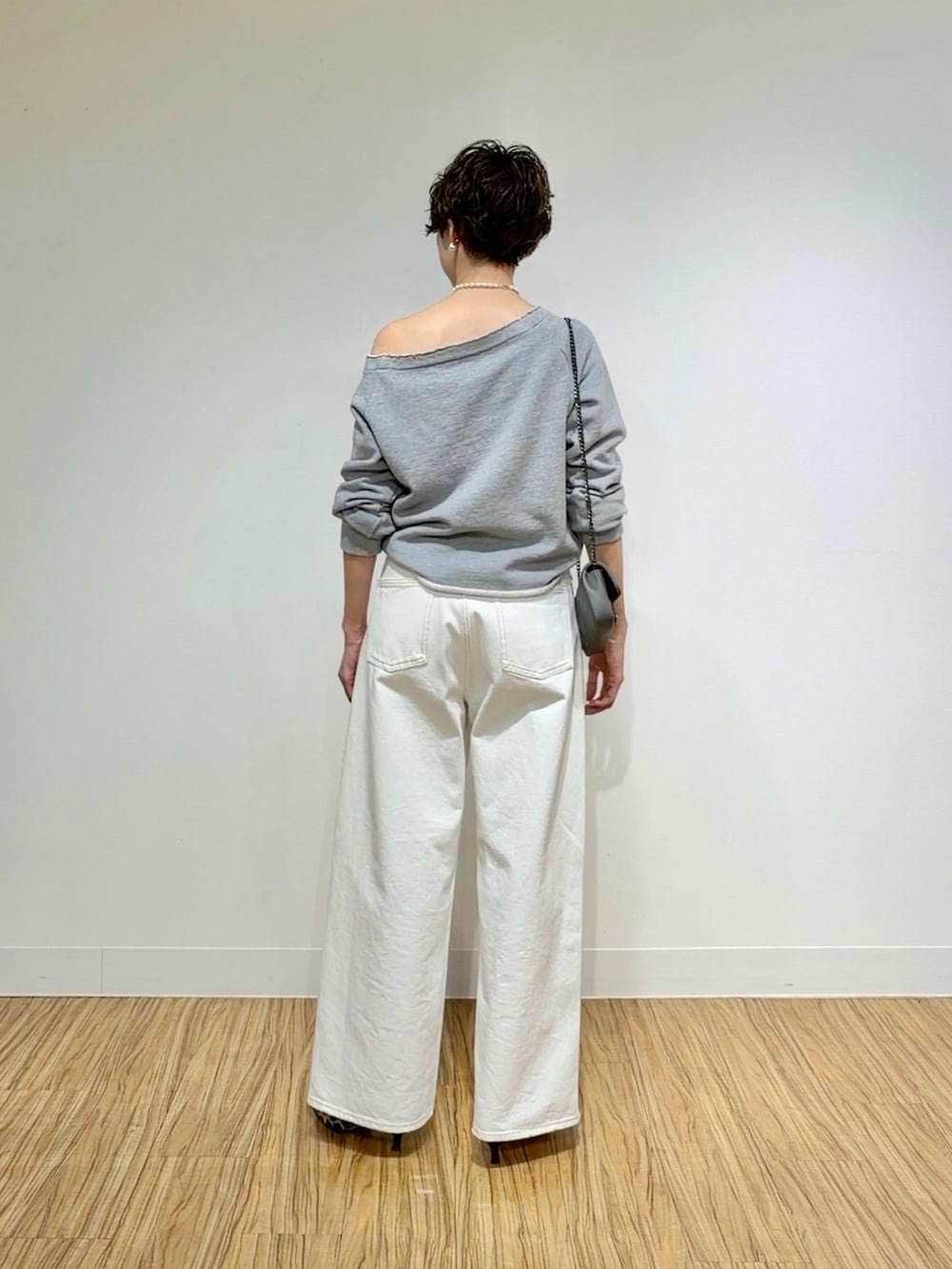グレー系のスウェット、ホワイト系のデニムパンツ、グレー系のショルダーバッグを着用したレディースの冬コーディネートの4枚目の写真