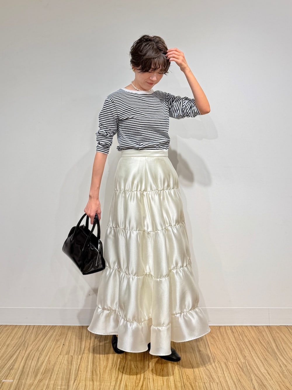 ブラック系のTシャツ/カットソー、ブラック系のボストンバッグ、ホワイト系のスカートを着用したレディースの冬コーディネートの2枚目の写真