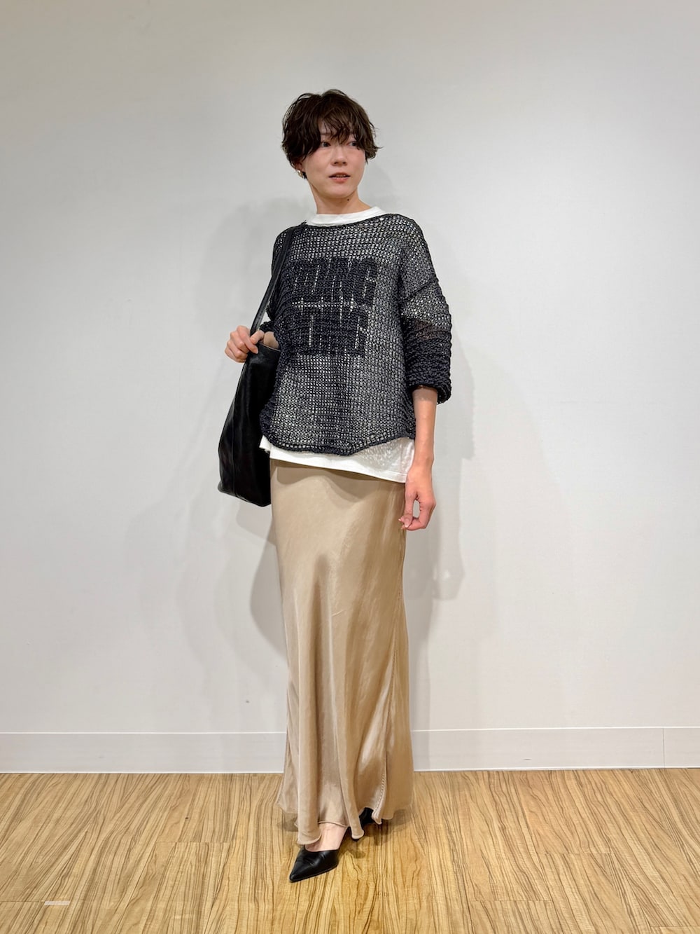 ホワイト系のTシャツ/カットソー、グレー系のニット/セーター、ベージュ系のスカートを着用したレディースの冬コーディネートの2枚目の写真