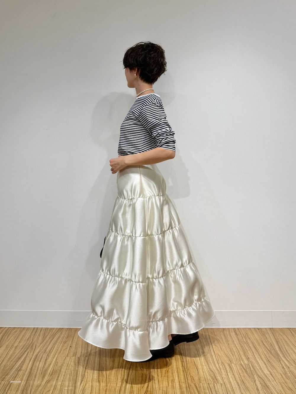 ブラック系のTシャツ/カットソー、ブラック系のボストンバッグ、ホワイト系のスカートを着用したレディースの冬コーディネートの5枚目の写真