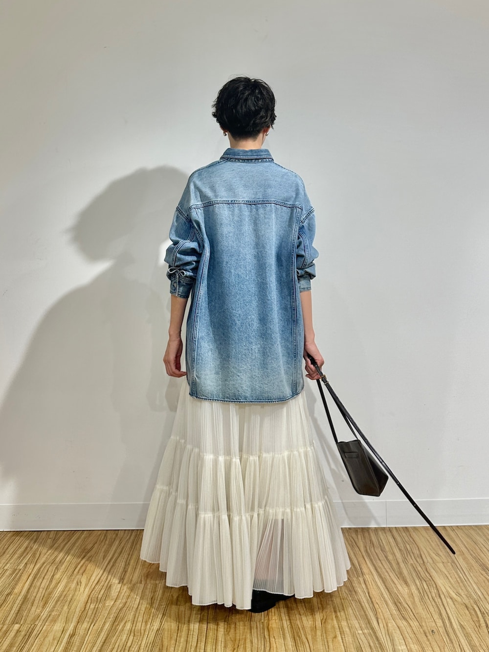 ブルー系のシャツ/ブラウス、ホワイト系のスカート、ブラウン系のショルダーバッグを着用したレディースの冬コーディネートの4枚目の写真