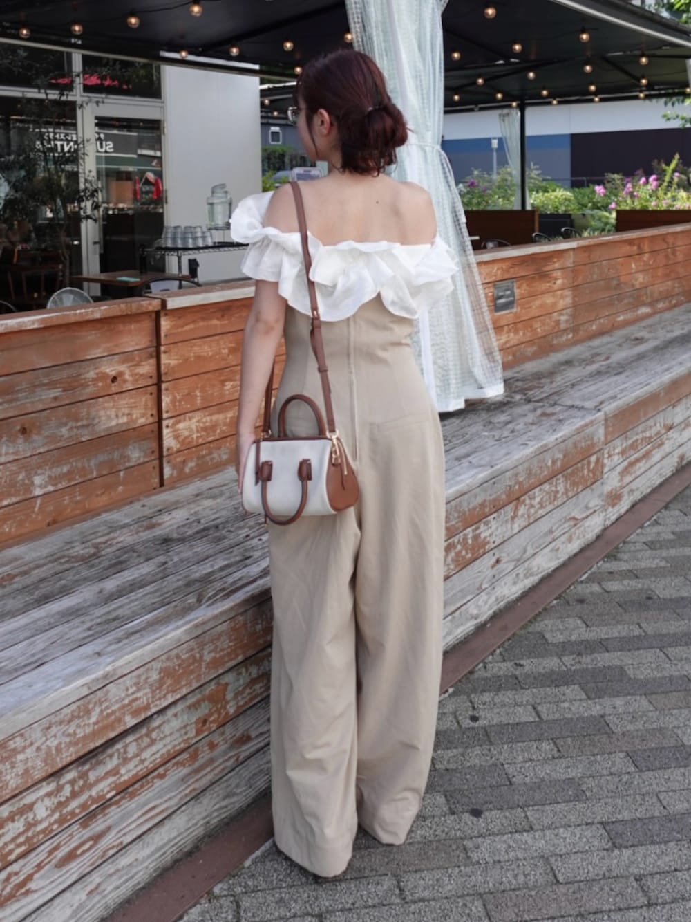 グレー系のトートバッグ、ブラウン系のパンプス、ホワイト系のニット/セーターを着用したレディースの夏コーディネートの2枚目の写真