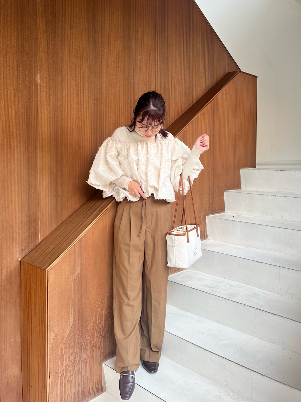 ホワイト系のシャツ/ブラウス、ホワイト系のニット/セーター、ブラウン系のパンツを着用したレディースの秋コーディネートの2枚目の写真