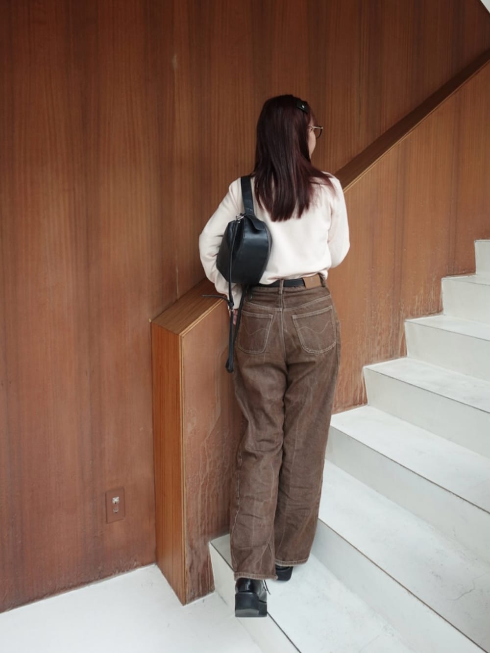 ブラック系のトートバッグ、ブラウン系のデニムパンツ、ブラック系のローファーを着用したレディースの秋コーディネートの2枚目の写真