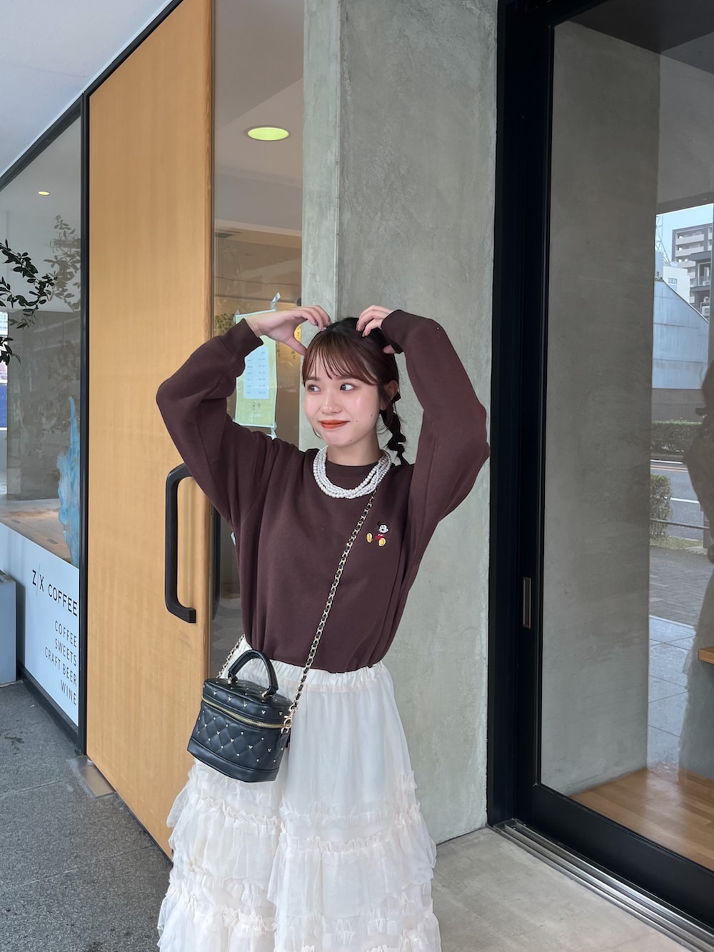 ブラウン系のスウェット、ブラック系のショルダーバッグ、ホワイト系のスカートを着用したレディースの秋コーディネートの3枚目の写真