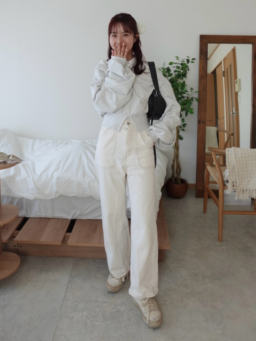 グレー系のスウェット、ホワイト系のデニムパンツ、ホワイト系のスニーカーを着用したレディースの春コーディネートの2枚目の写真