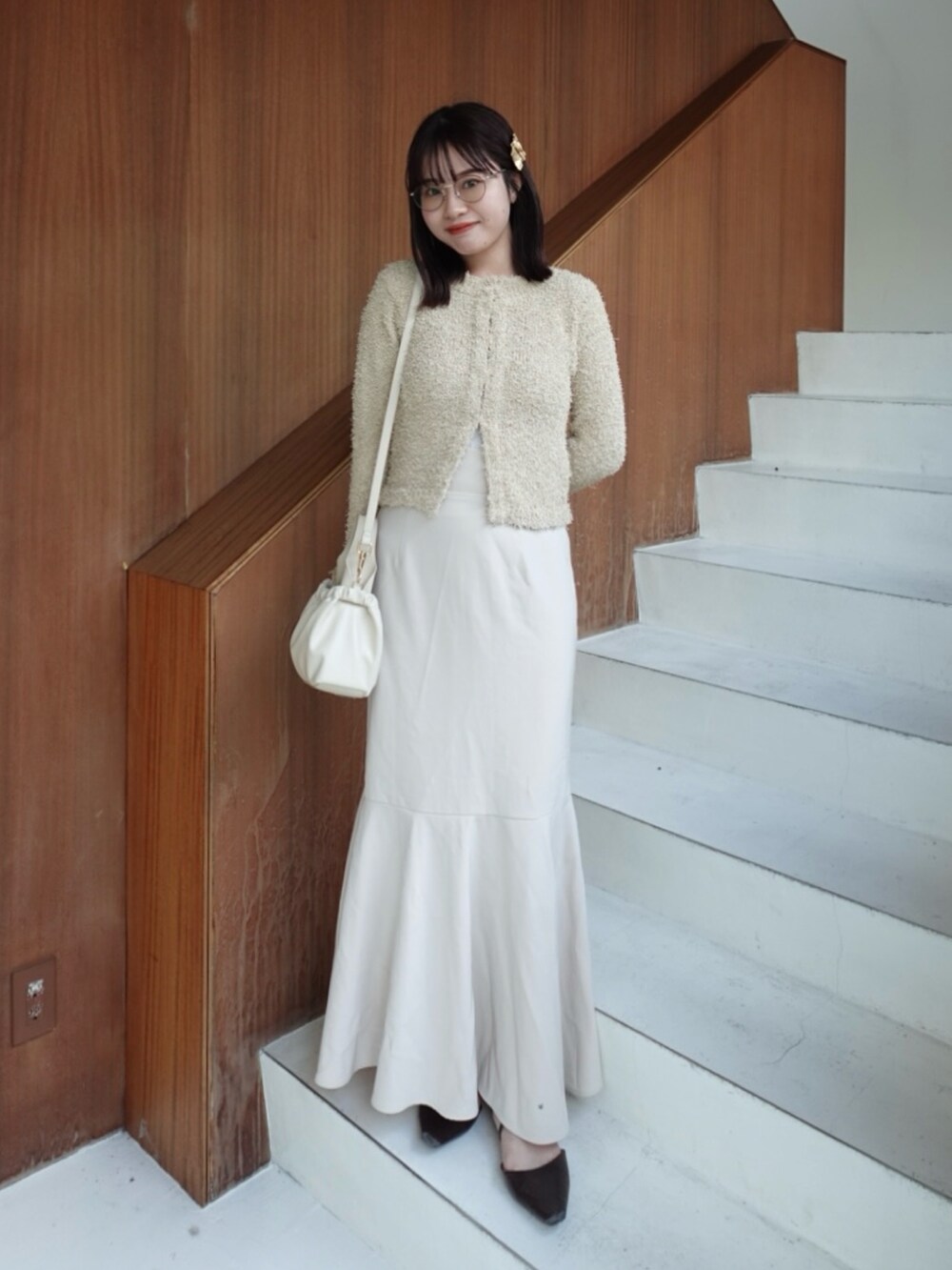 ベージュ系のカーディガン/ボレロ、ブラウン系のパンプス、ホワイト系のスカートを着用したレディースの春コーディネートの2枚目の写真