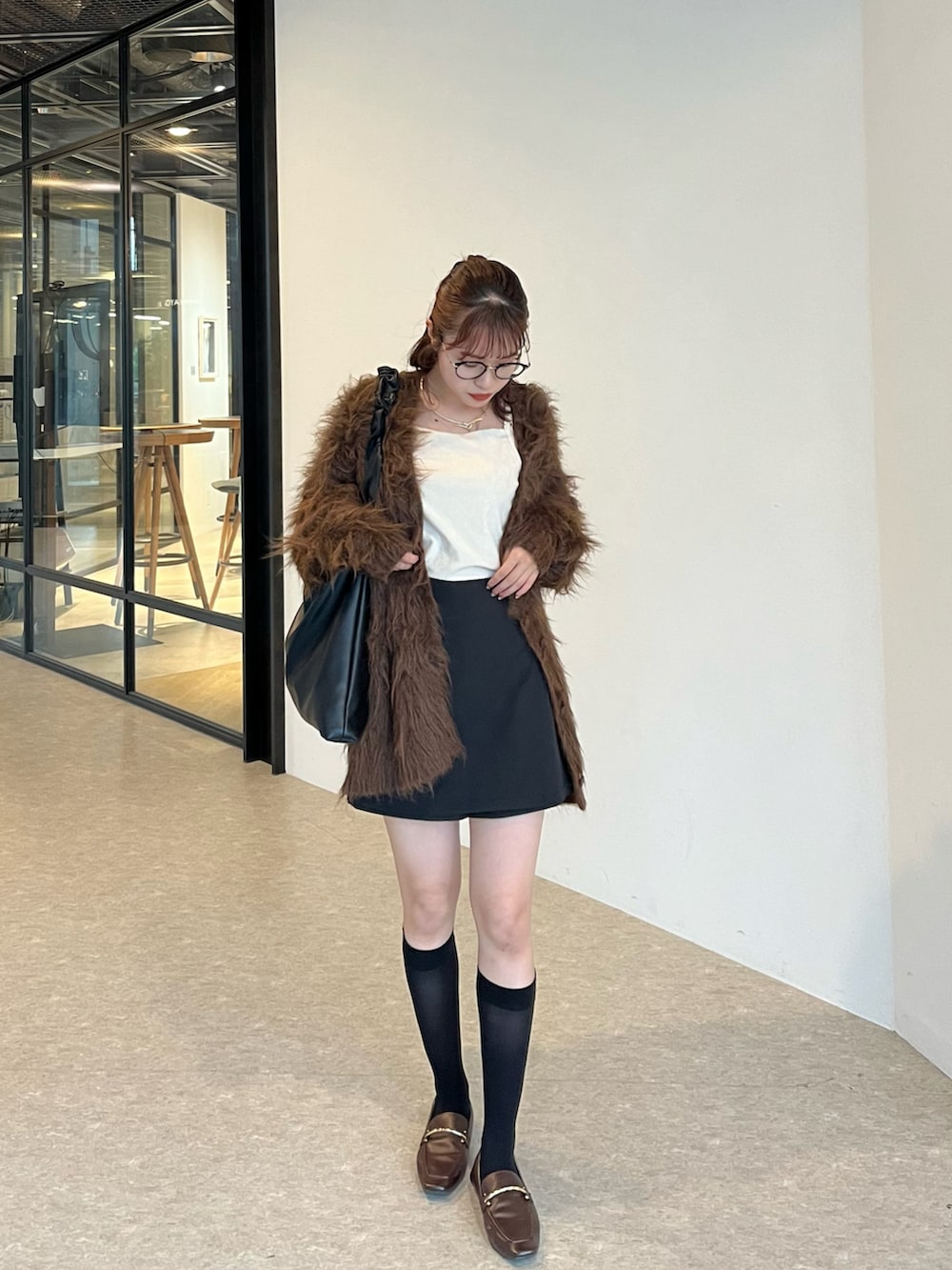 ブラウン系のカーディガン/ボレロ、ホワイト系のキャミソール、ブラック系のスカートを着用したレディースの秋コーディネートの2枚目の写真