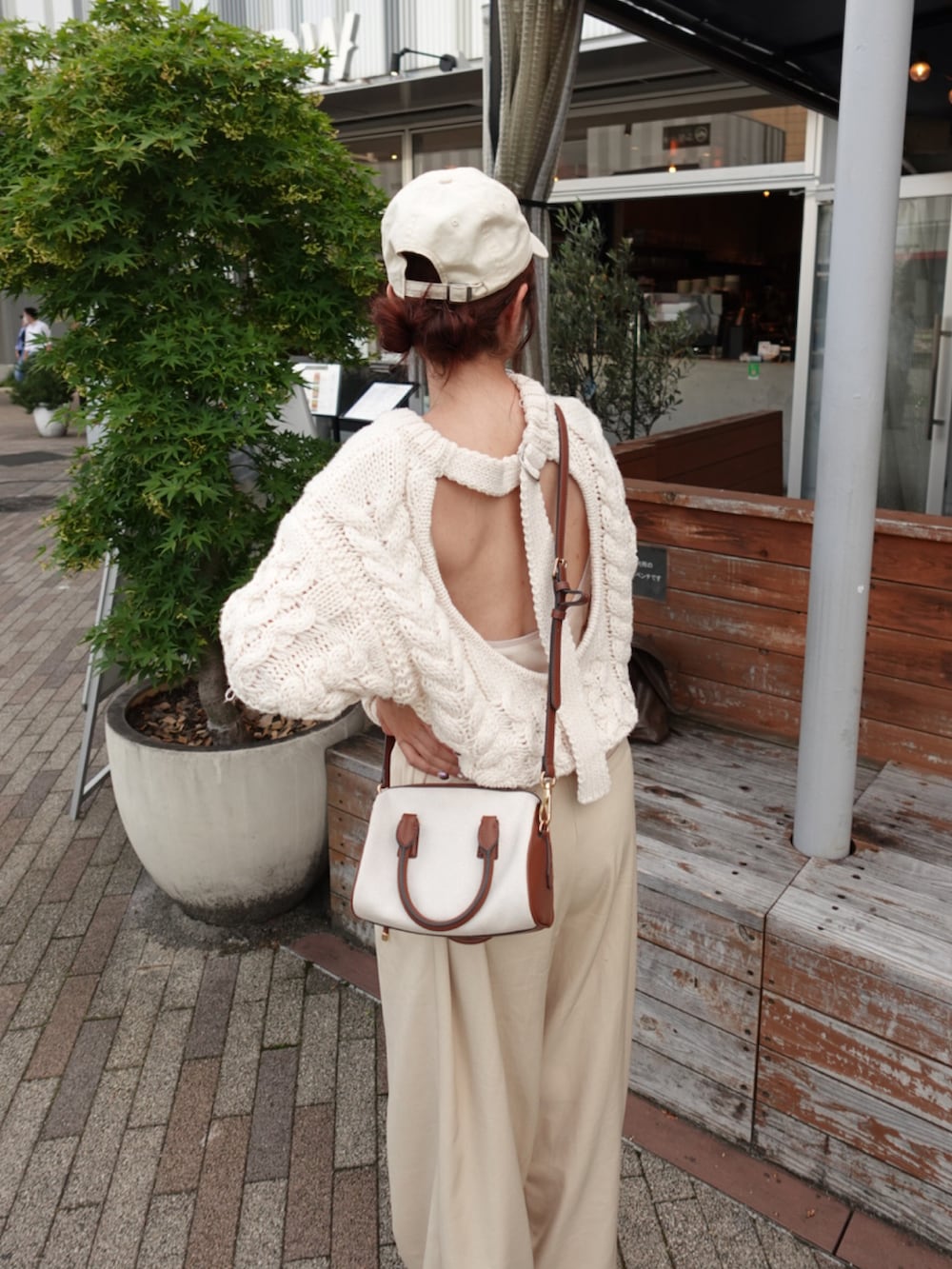 ベージュ系のサロペット/オーバーオール、ホワイト系のニット/セーター、グレー系のトートバッグを着用したレディースの夏コーディネートの3枚目の写真