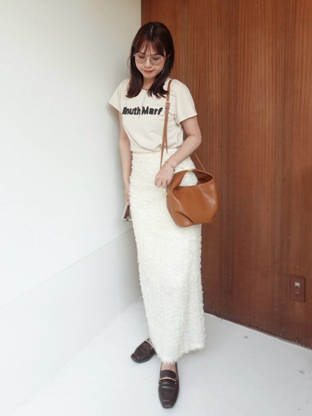 ホワイト系のスカート、ベージュ系のTシャツ/カットソー、ブラウン系のローファーを着用したレディースの夏コーディネートの2枚目の写真