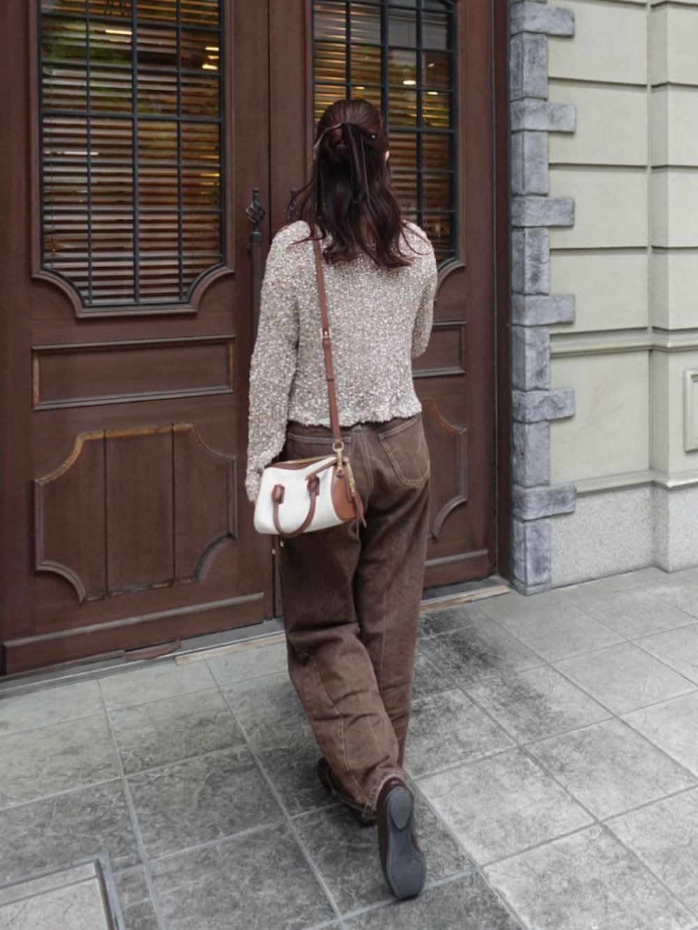 ベージュ系のニット/セーター、ブラウン系のデニムパンツ、ブラウン系のローファーを着用したレディースの秋コーディネートの4枚目の写真