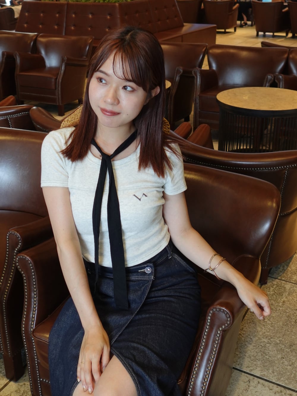 ブルー系のデニムスカート、ブラック系のパンプス、ブラック系のトートバッグを着用したレディースの夏コーディネートの3枚目の写真