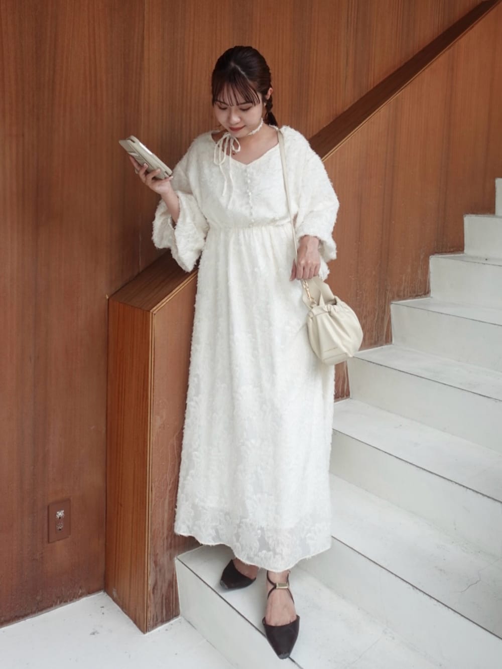 ホワイト系のワンピース、ブラウン系のパンプス、ホワイト系のショルダーバッグを着用したレディースの夏コーディネートの2枚目の写真