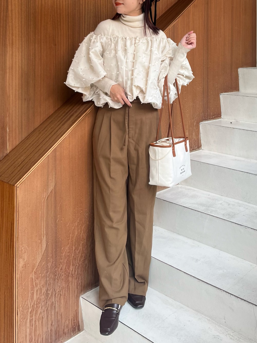 ホワイト系のシャツ/ブラウス、ホワイト系のニット/セーター、ブラウン系のパンツを着用したレディースの秋コーディネートの3枚目の写真