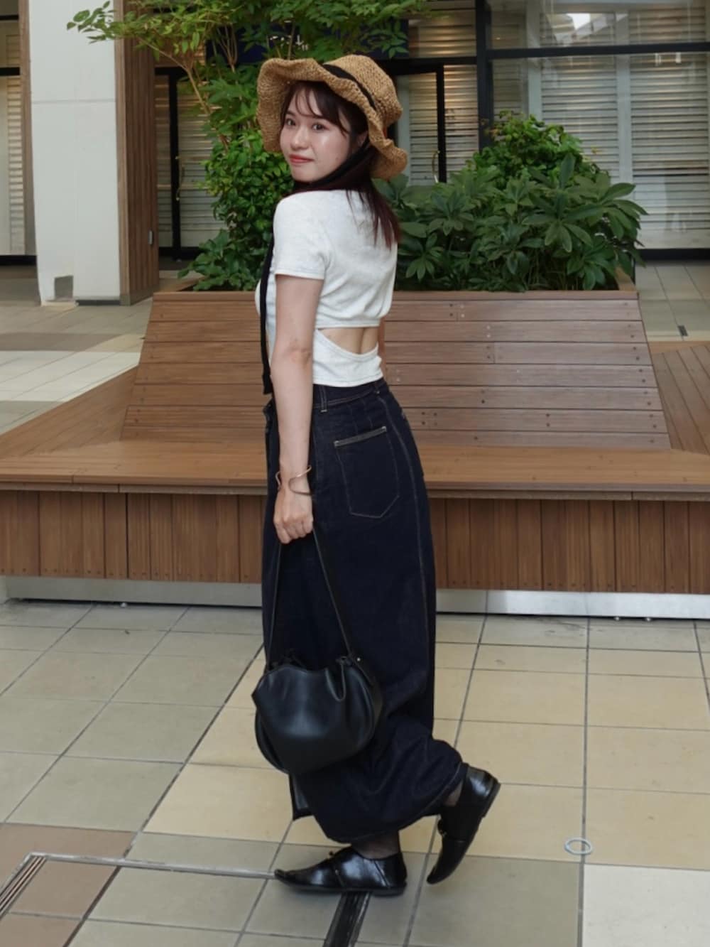 ブルー系のデニムスカート、ブラック系のパンプス、ブラック系のトートバッグを着用したレディースの夏コーディネートの2枚目の写真