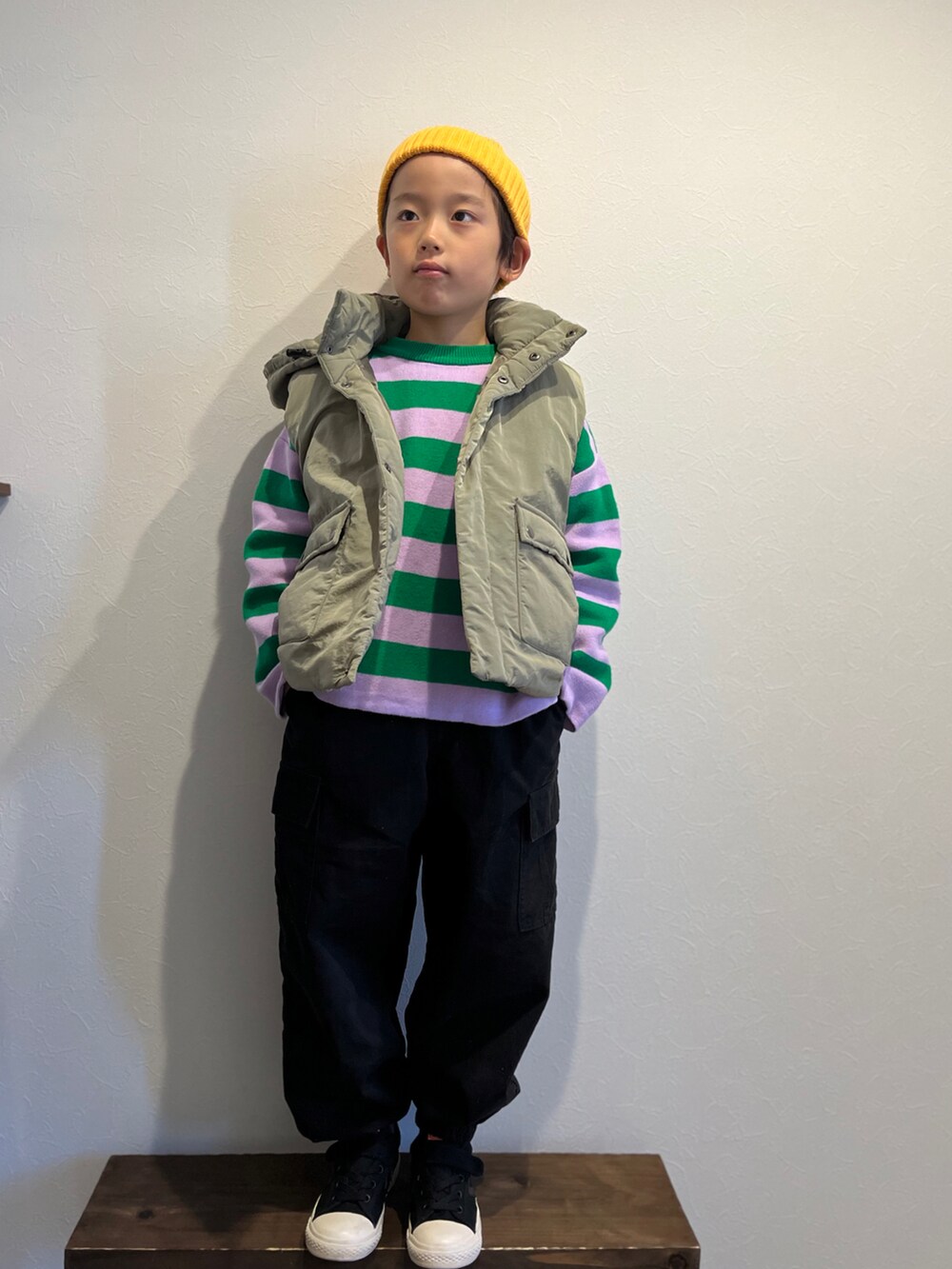 グリーン系のダウンベスト、グリーン系のニット/セーター、ブラック系のカーゴパンツを着用したキッズの冬コーディネートの2枚目の写真