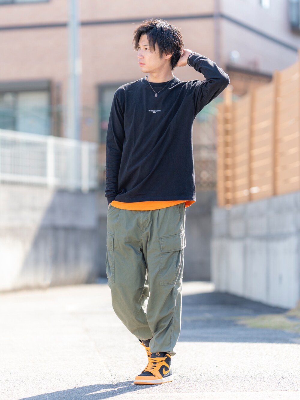 ブラック系のTシャツ/カットソー、オレンジ系のTシャツ/カットソー、グリーン系のカーゴパンツを着用したメンズの春コーディネートの2枚目の写真