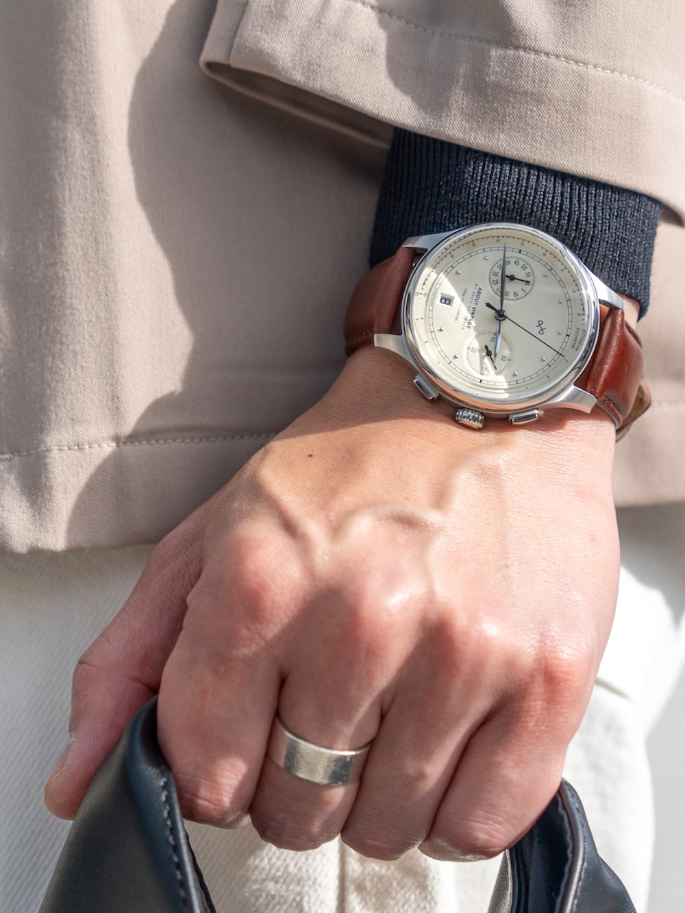 ベージュ系のノーカラージャケット、ブラック系のニット/セーター、ホワイト系のパンツを着用したメンズの春コーディネートの2枚目の写真