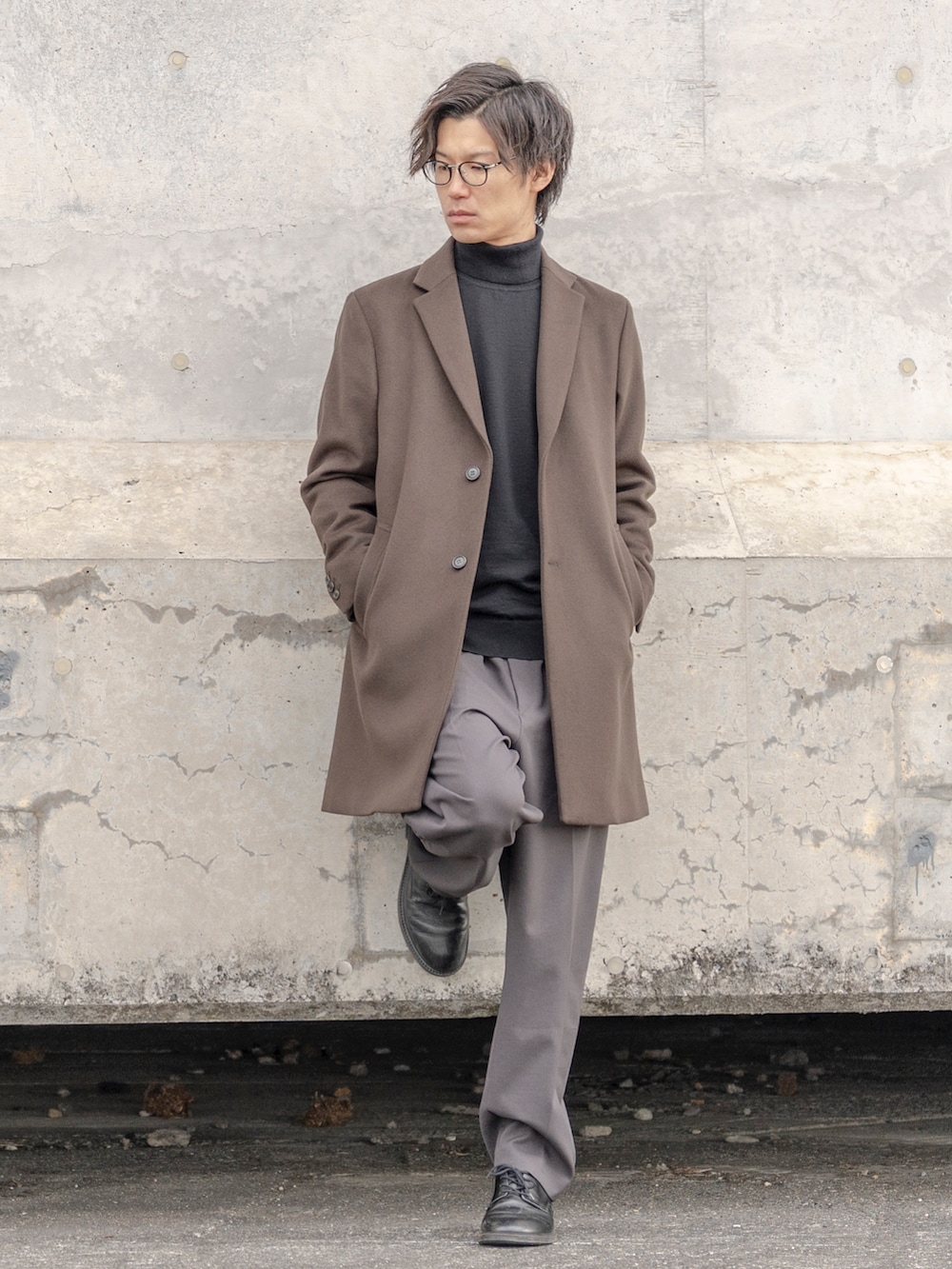 グリーン系のチェスターコート、グレー系のその他パンツ、ブラック系のシューズを着用したメンズの冬コーディネートの2枚目の写真